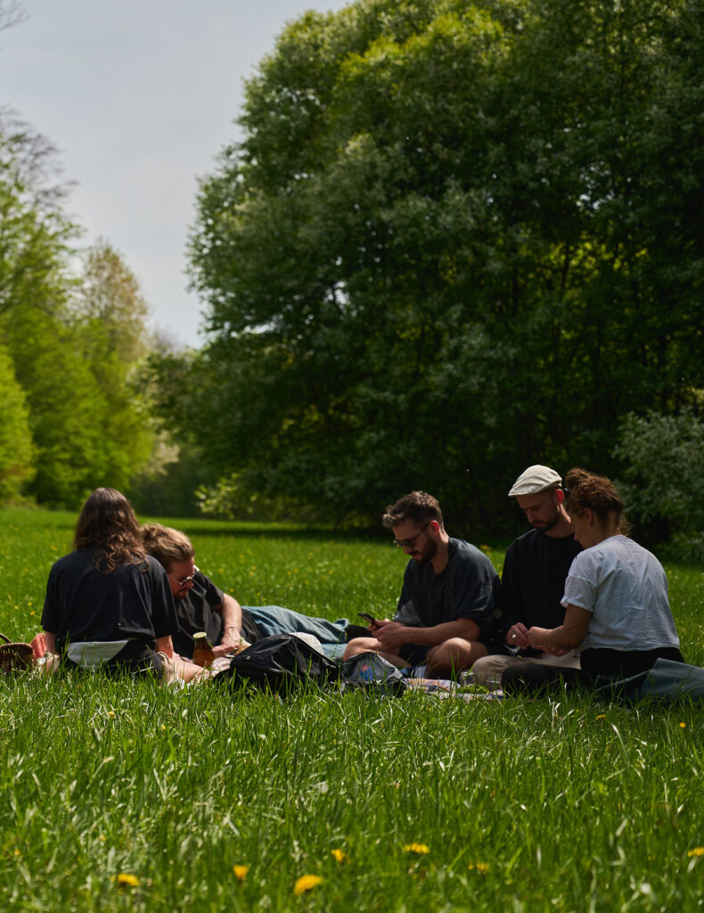 Menschengruppe sitzt auf der Wiese versamelt zu einem Picknick