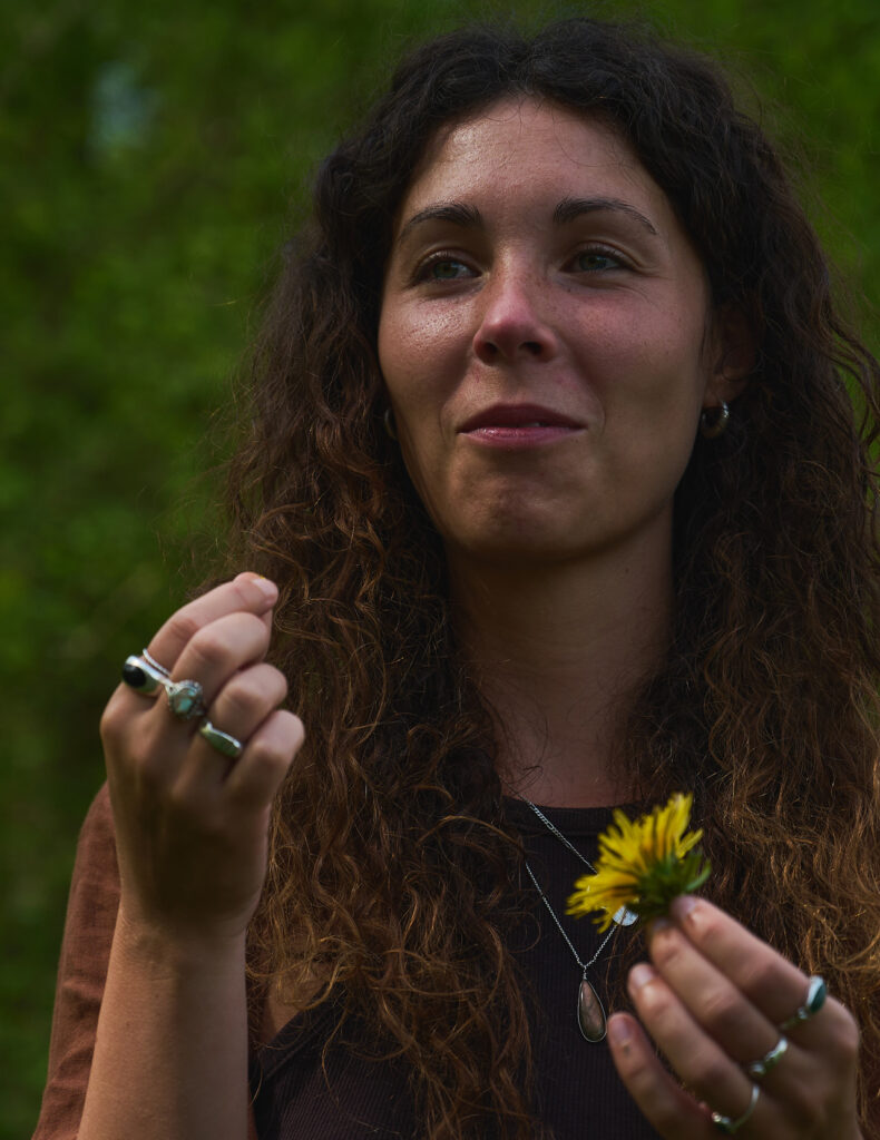 Frau in der Sonne probiert eine Löwenzahnblüte